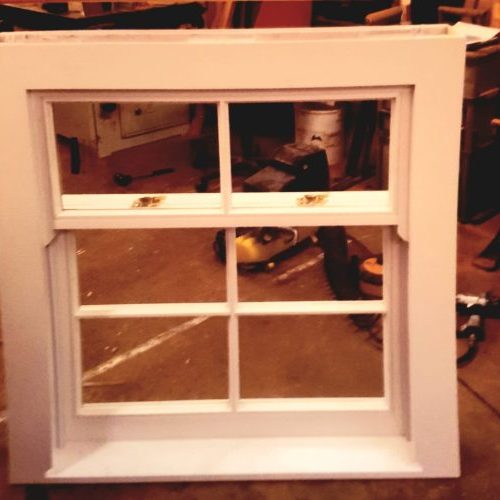 Traditional timber sash window under construction in a joinery workshop, ready for installation.
